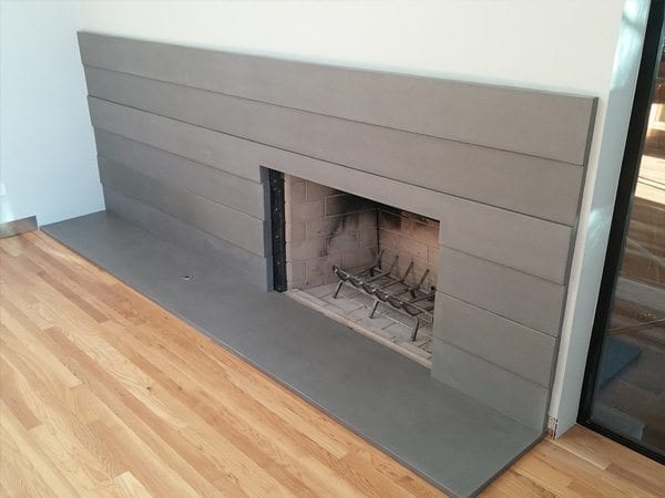 Fireplaces don’t always have to look old an. The thin gray modern concrete panels create wonderful modern look for this fire place surround.